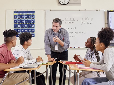 AP Precalculus teacher with four high school students in a classroom